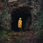 Overcoming Fear - a person in a yellow jacket is standing in a cave