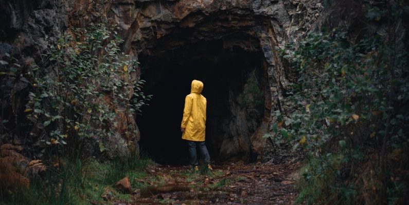 Overcoming Fear - a person in a yellow jacket is standing in a cave
