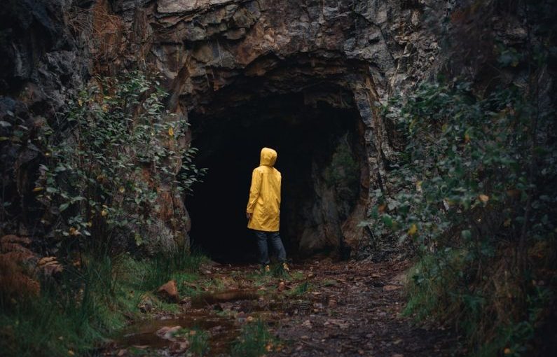Overcoming Fear - a person in a yellow jacket is standing in a cave