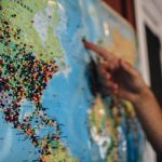 Document Travel - a person pointing at a map with pins on it
