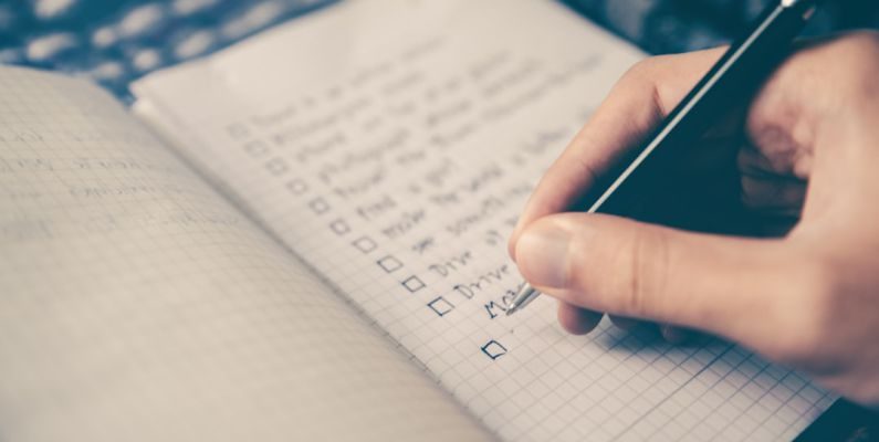 Packing Checklist - person writing bucket list on book