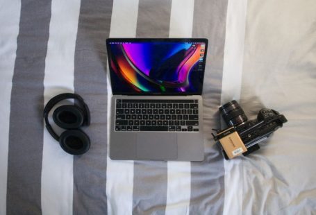 Travel Tech - a laptop computer sitting on top of a bed next to a camera