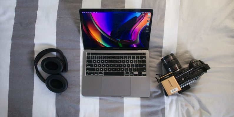 Travel Tech - a laptop computer sitting on top of a bed next to a camera
