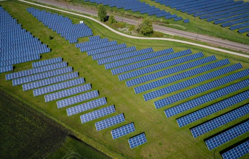 Renewable Energy - aerial photography of grass field with blue solar panels
