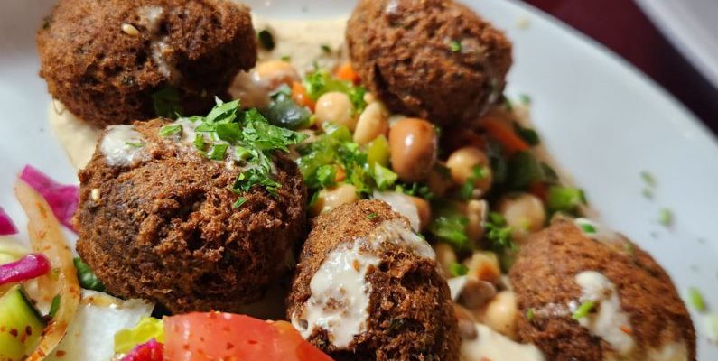 Plant-based Cuisine - a white plate topped with meatballs and a salad